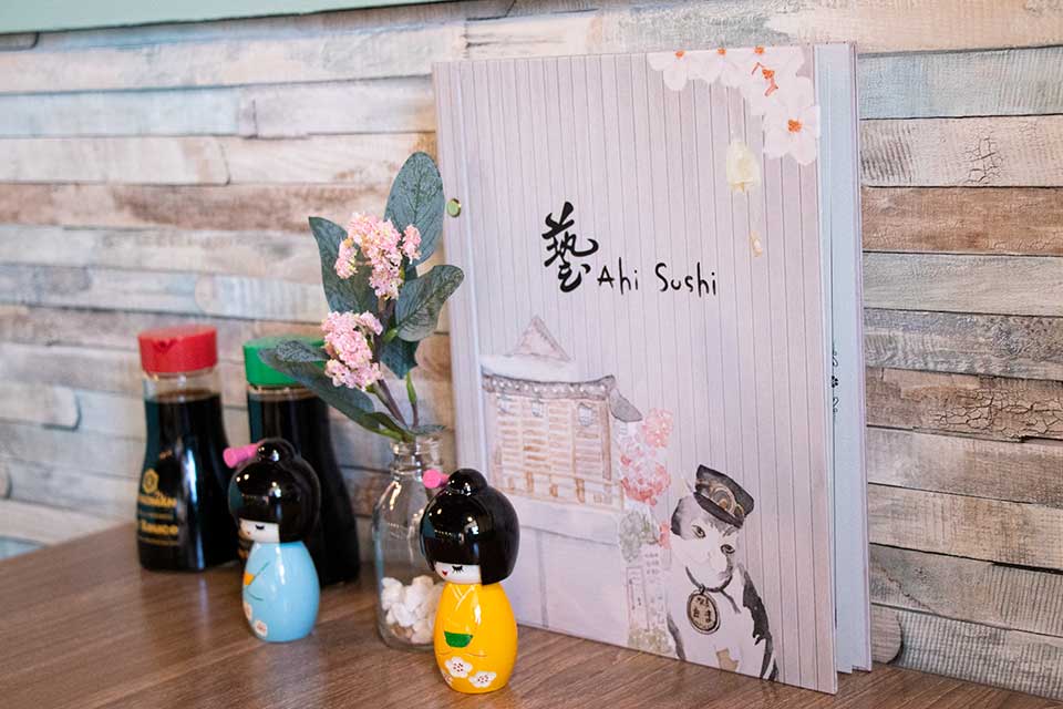 Ahi Sushi menu, dolls, and soy sauce on a table top